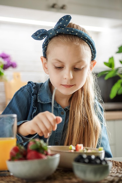 La petite fille mignonne mange la salade de fruit