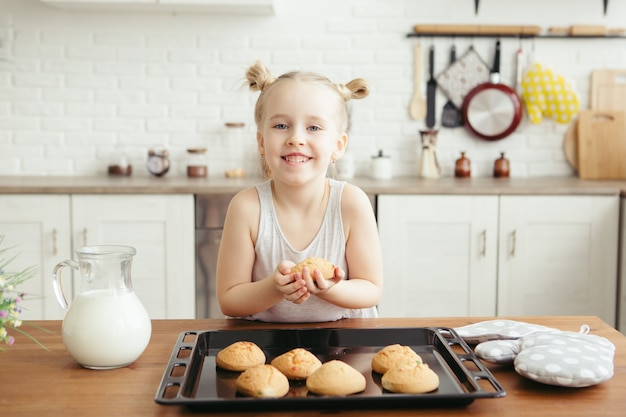 Petite fille mignonne mangeant des biscuits fraîchement cuits au four dans la cuisine. Famille heureuse. Tonifiant.