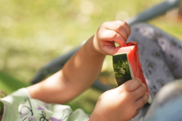 Petite fille mignonne mangeant la pastèque sur une chaise longue dans le jardin en été