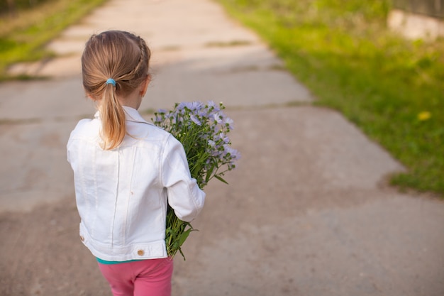 Petite fille mignonne marchant avec un bouquet de fleurs