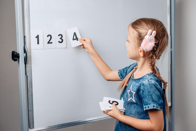 Petite fille mignonne de marionnettes arrangeant les nombres dans le bon ordre. Bel enfant tenant une carte avec le numéro 4. Concept de mathématiques. photo avec du bruit