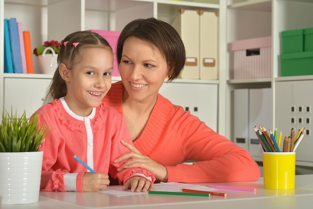 Petite fille mignonne avec mère dessinant une photo à la maison