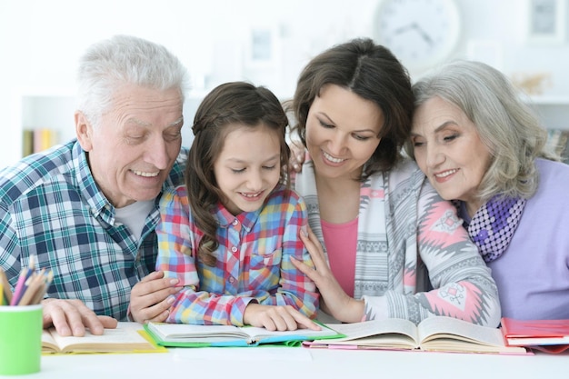 Petite fille mignonne avec la mère et les grands-parents étudiant