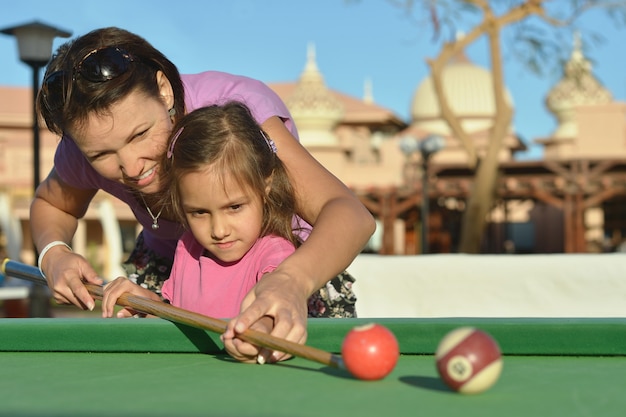 Petite fille mignonne avec la mère jouant au billard