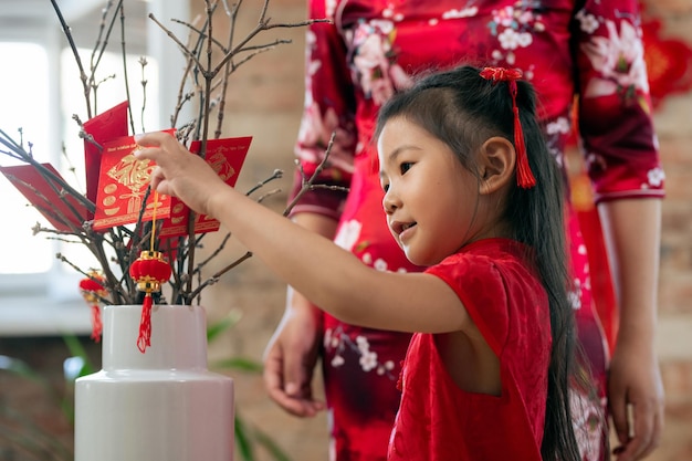 Petite fille mignonne mettant la lanterne décorative sur des branches