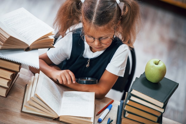 La petite fille mignonne avec des nattes est dans la bibliothèque