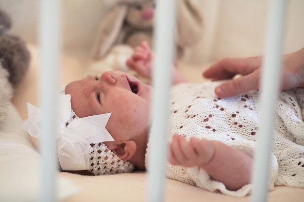 La petite fille mignonne nouveau-née se trouve dans le berceau et regarde la mère