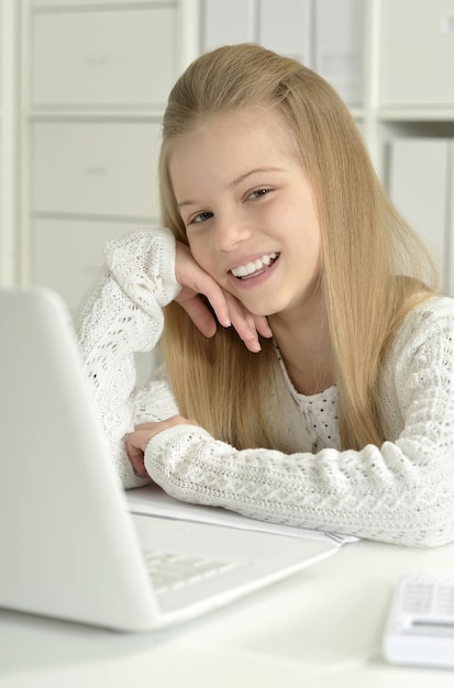 Petite fille mignonne et ordinateur portable à la maison