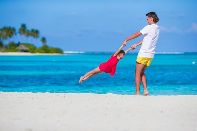 Petite fille mignonne et papa pendant les vacances à la plage tropicale