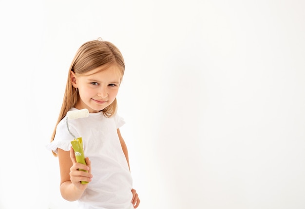 Petite Fille Mignonne Peint Un Mur Avec Un Rouleau à Peinture