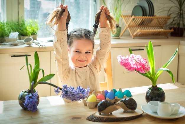 Une petite fille mignonne peint des oeufs de Pâques fleurs de printemps jacinthes oeufs colorés décoration de vacances