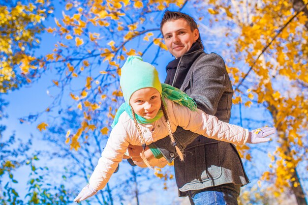 Petite fille mignonne avec père heureux s'amuser dans le parc automne par une journée ensoleillée