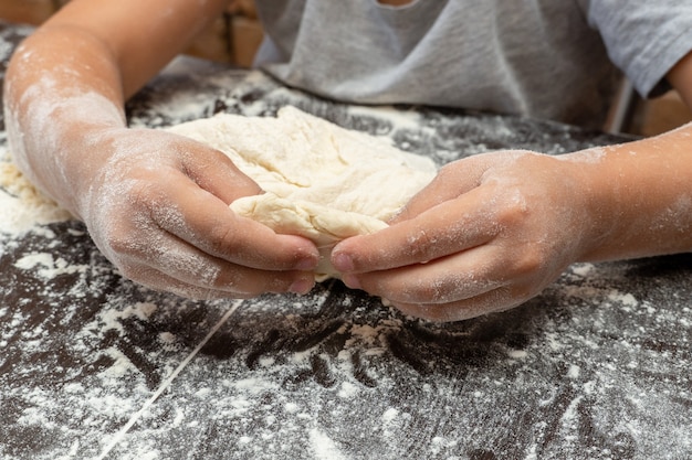 Petite fille mignonne pétrissant la pâte, préparant la pâte pour la cuisson