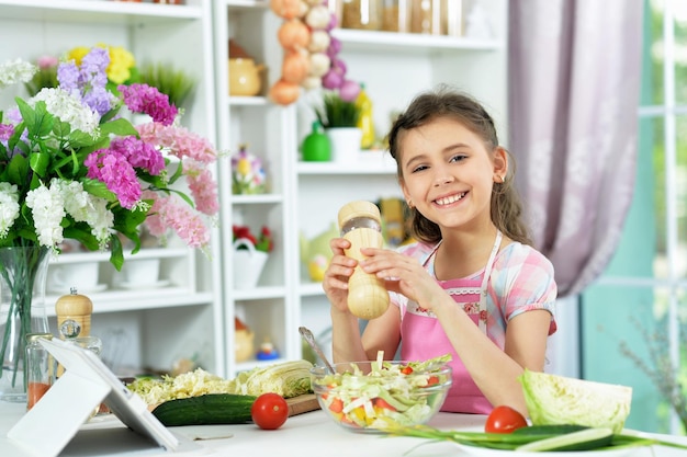 Petite fille mignonne préparant la salade fraîche