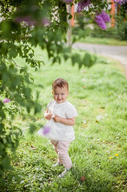 Petite fille mignonne près du lilas en fleurs. Printemps.