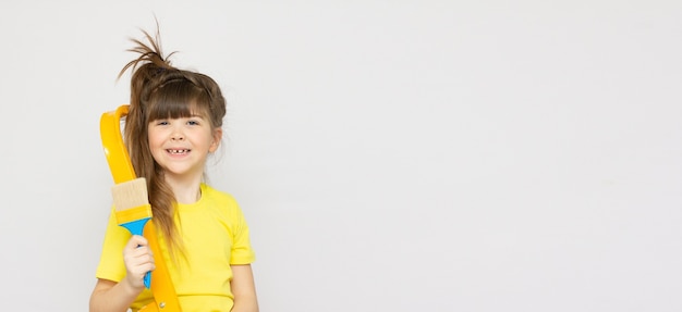 Petite fille mignonne prête à peindre le mur avec la grande brosse, au-dessus de l'espace de copie de bannière de fond blanc