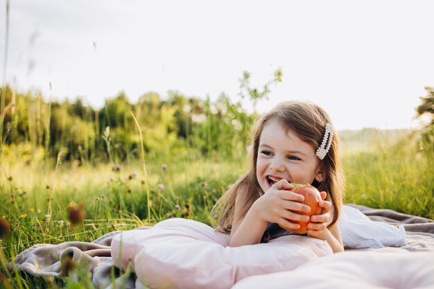 Petite fille mignonne ramassant des pommes dans un fond d'herbe verte au jour ensoleillé