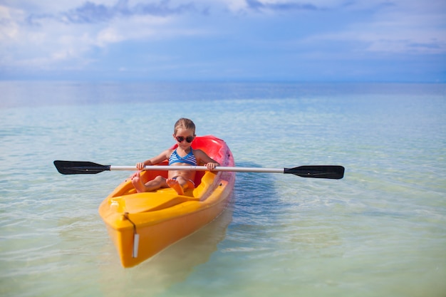 Petite fille mignonne ramer un bateau dans la mer bleue