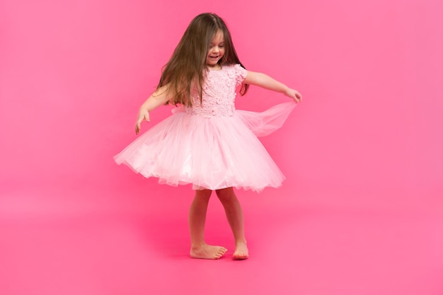 La petite fille mignonne rêve de devenir une ballerine. Petite danseuse. Studio Shoot Sur Fond Rose.