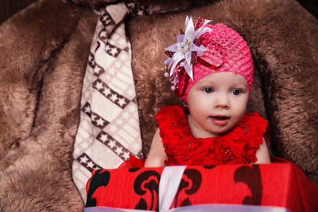 Petite fille mignonne en robe rouge avec gros ours en peluche et cadeaux