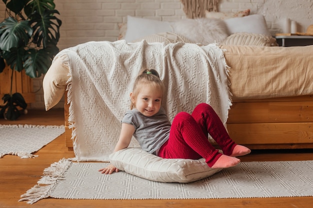 Petite fille mignonne s'amuse près du lit.