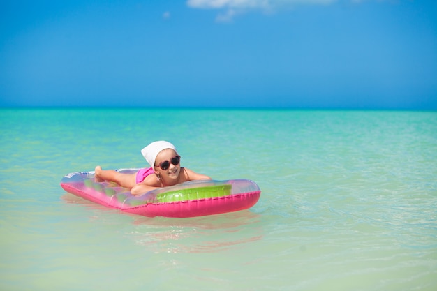 Petite fille mignonne se faire bronzer sur air-lit rose dans la mer chaude