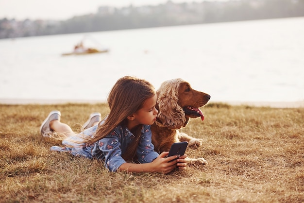 Une petite fille mignonne se promène avec son chien à l'extérieur par beau temps