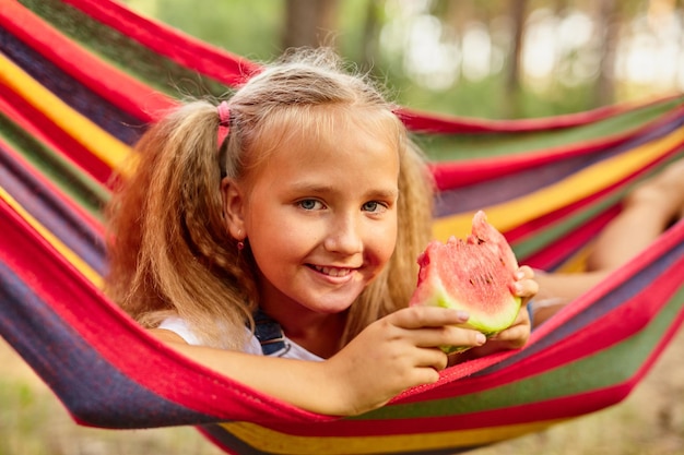 Petite fille mignonne se reposant dans un hamac coloré dans la forêt