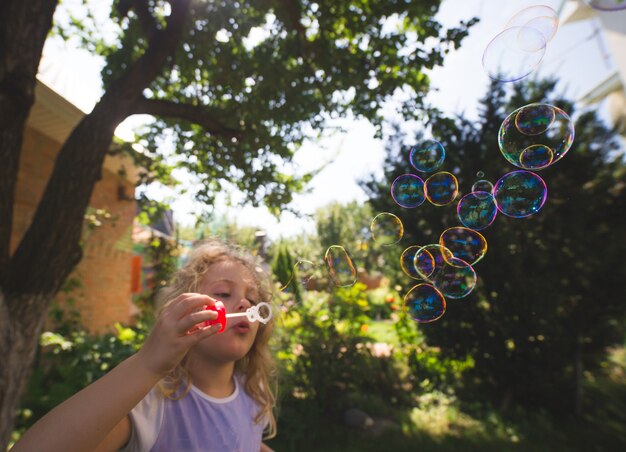 Photo la petite fille mignonne souffle des bulles de savon.