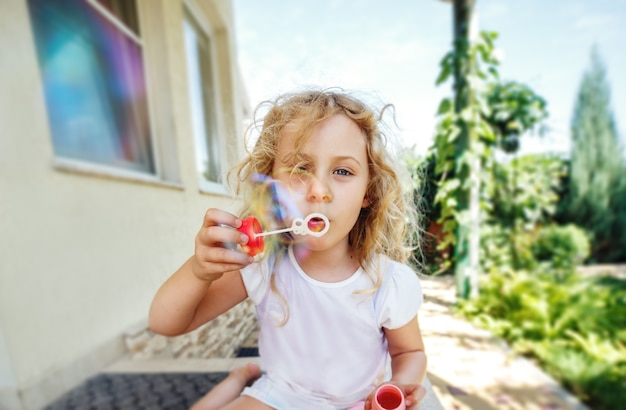 La petite fille mignonne souffle des bulles de savon.