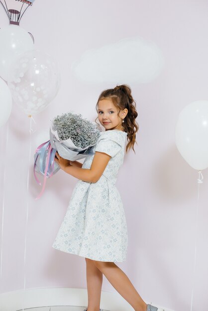 Une petite fille mignonne sourit et pose avec un bouquet de fleurs