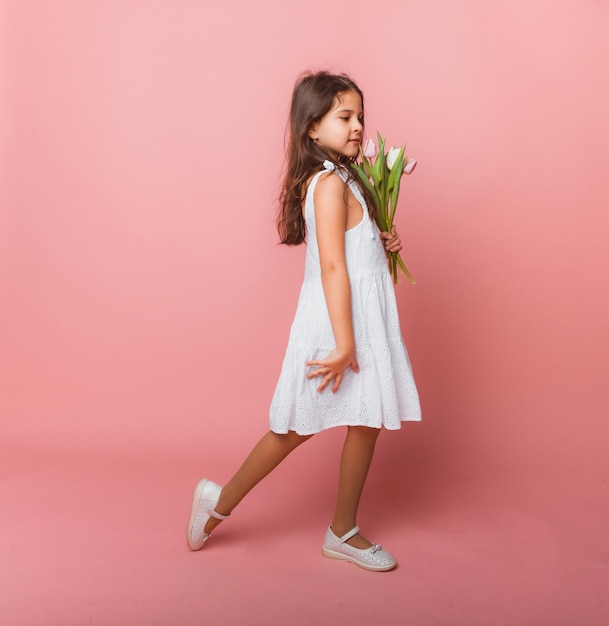 Petite fille mignonne tenant un bouquet de tulipes sur fond rose Bonne journée de la femme Place pour le texte Émotions vives 8 mars