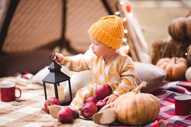 Petite fille mignonne tenant la citrouille et la bougie savoureuses rouges de pommes