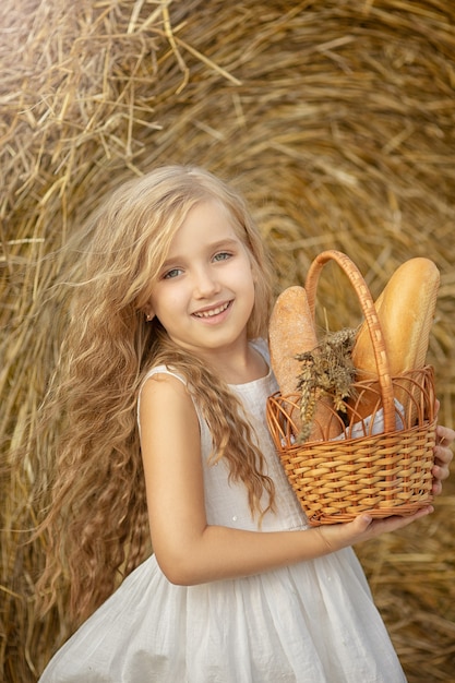 Petite fille mignonne sur le terrain avec un panier de pain