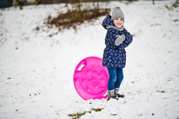 Petite fille mignonne avec des traîneaux de soucoupe dehors le jour d'hiver.