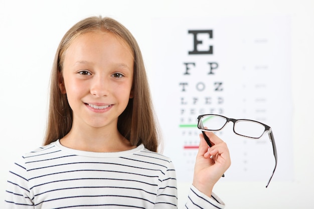 La petite fille mignonne vérifie la vue avec un essai de vue d'ophtalmologiste