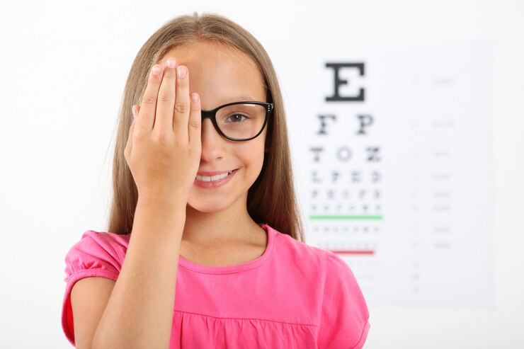 La petite fille mignonne vérifie la vue avec un essai de vue d'ophtalmologiste
