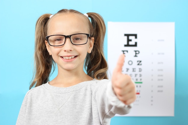 La petite fille mignonne vérifie la vue avec un essai de vue d'ophtalmologiste