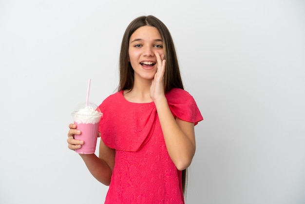 Petite fille avec milkshake aux fraises sur fond blanc isolé criant avec la bouche grande ouverte