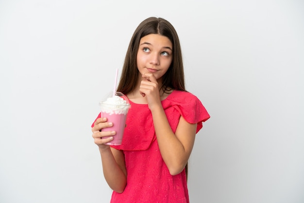 Petite fille avec milkshake aux fraises sur fond blanc isolé et levant