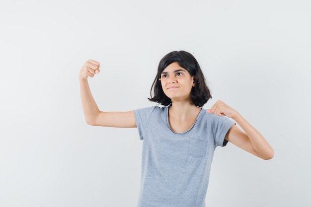 Petite fille montrant le geste gagnant en t-shirt et à la béatitude, vue de face.