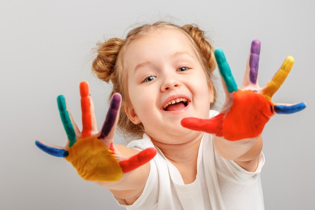 Petite fille montre des mains peintes avec de la peinture.