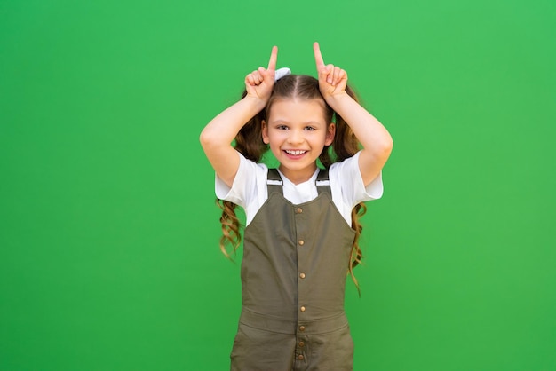 Une petite fille montre de petites cornes avec ses mains L'enfant montre des cornes avec ses mains