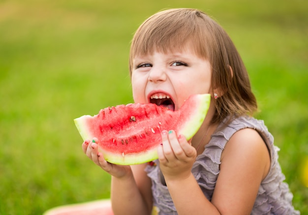 Petite fille avec un morceau de pastèque dans les mains