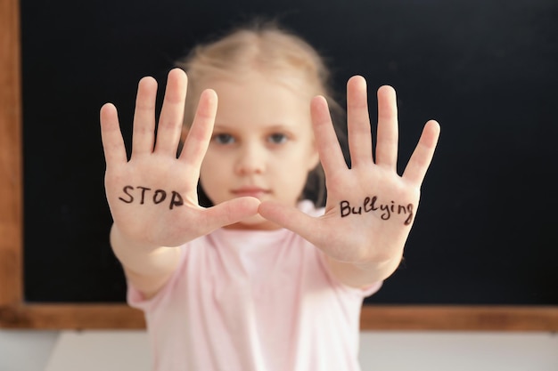 Petite fille avec des mots Arrêtez l'intimidation sur fond sombre