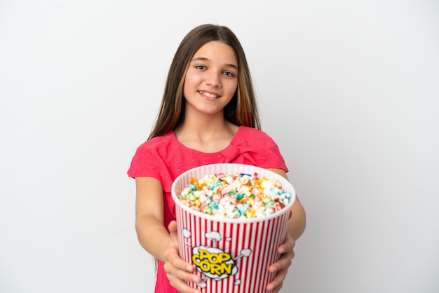 Petite fille sur un mur blanc isolé tenant un grand seau de pop-corn