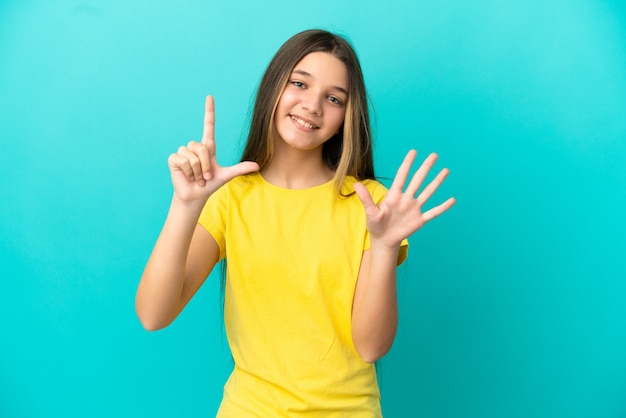 Petite fille sur un mur bleu isolé comptant sept avec les doigts