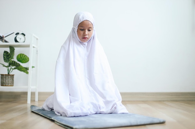 Photo une petite fille musulmane asiatique faisant un mouvement de geste dans la procédure de la salat le fidèle procède à