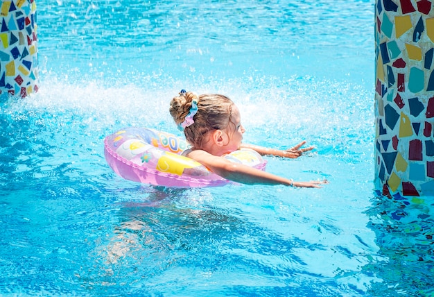 La petite fille nage avec un cercle dans la piscine