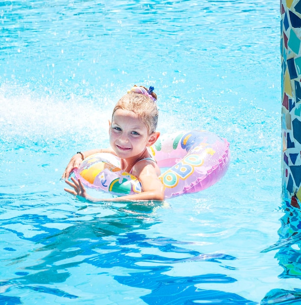 La petite fille nage avec un cercle dans la piscine